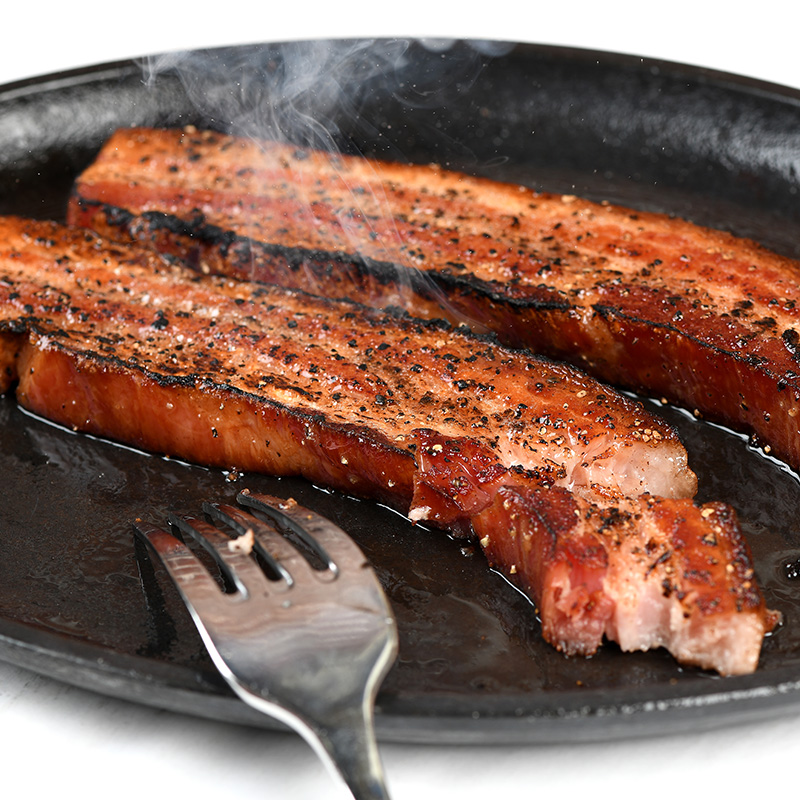Baker's Bacon sous vide sliced and cooking on a skillet